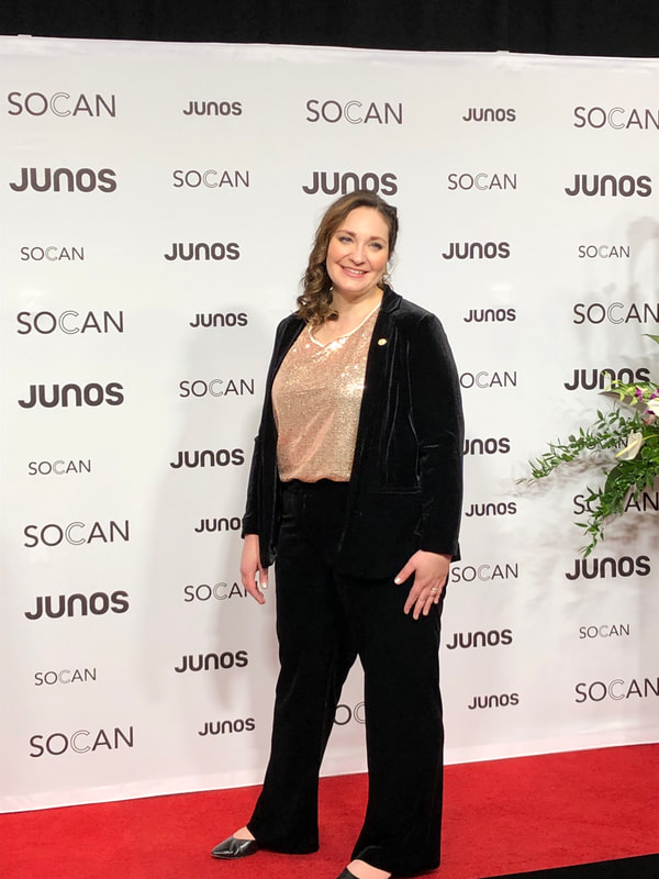 Beppie on the red carpet at the JUNOS is 2019. She is wearing a black velvet pant suit with a gold shirt underneath. 